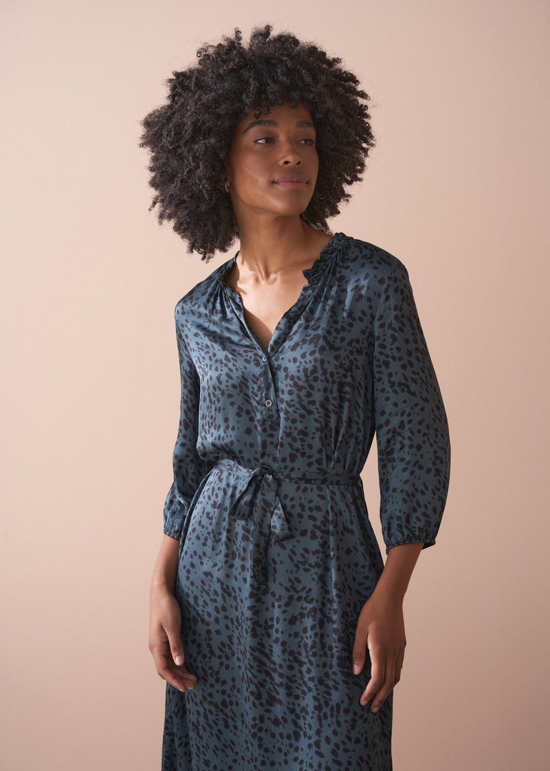 Woman wearing a patterned dress against a beige background