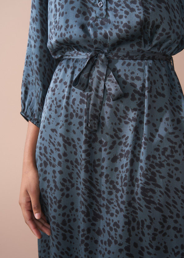 Blue dress with black leopard print pattern on a beige background
