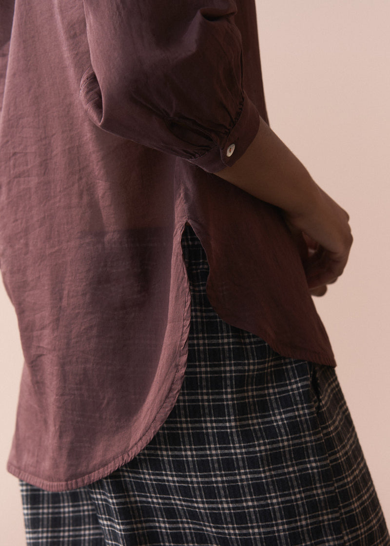 Person wearing a maroon shirt and plaid pants against a beige background