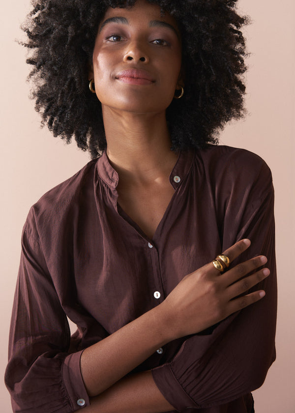 Woman wearing a brown semi sheer shirt with a neutral background