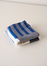 Folded striped towel with blue, white, and beige colors on a light background