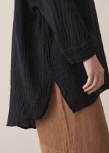 Woman wearing a black cotton oversized blouse and brown linen trousers