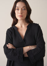 Woman wearing a black cotton oversized blouse and brown linen trousers