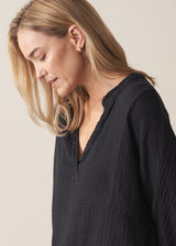Woman wearing black crinkled cotton a-line top with beige linen trousers