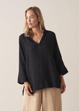 Woman wearing black crinkled cotton a-line top with beige linen trousers