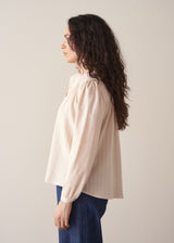 Woman wearing blush pink pinstripe blouse with puff sleeves