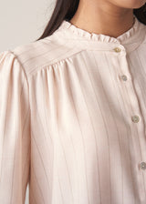 Woman wearing a light pink blouse with pinstripes and long sleeves with dark navy trousers
