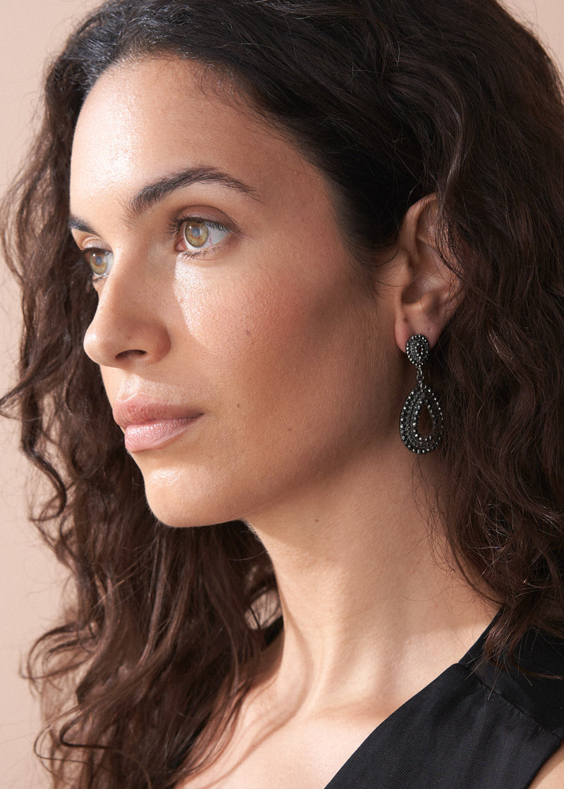 A model wearing the Ainsley Earrings featuring a striking teardrop silhouette embellished with jet-black crystals