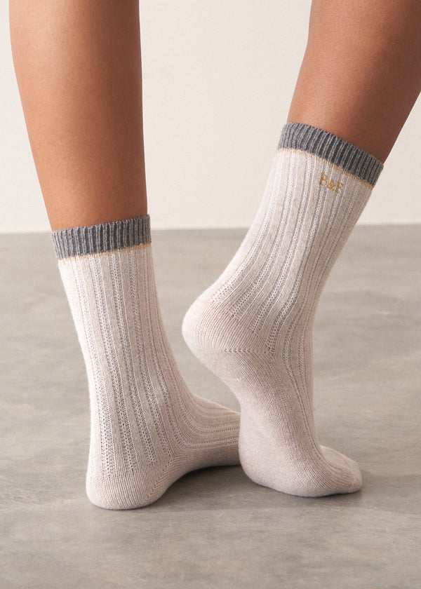 Person wearing heavy knit recycled wool blend socks in neutral and grey with metallic thread detailing and embroidered B&F monogram