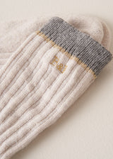 Close up of "B&F" monochrome logo, on heavy knit recycled wool blend socks in neutral and grey with metallic thread detailing