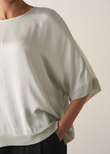 Close up of woman wearing a pale green satin blouse top