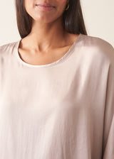 Woman wearing pearlescent light lilac satin top with navy check trousers and a dark plum chunky cardigan