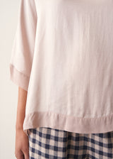 Woman wearing pearlescent light lilac satin top with navy check trousers and a dark plum chunky cardigan