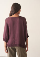 A woman wearing a plum satin top with khaki green trousers