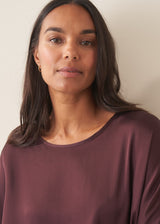 A woman wearing a plum satin top with khaki green trousers