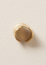 Side view of gold chunky wave ring on a light beige background