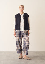 Woman wearing dark blue chunk knit waistcoat with white shirt and blue checked trousers