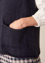 Woman wearing dark blue chunk knit waistcoat with white shirt and blue checked trousers