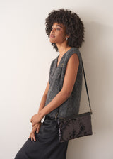 Woman holding a black clutch against a plain background