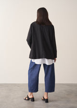 Woman wearing black oversized floppy jacket with a white shirt and blue jeans.