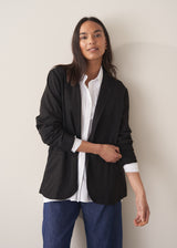Woman wearing black oversized floppy jacket with a white shirt and blue jeans.