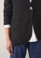 Woman wearing black oversized floppy jacket with a white shirt and blue jeans.