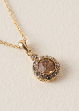 A close up of a pendant adorned with sparkling silver diamantes and a rich, amber-coloured crystal.
