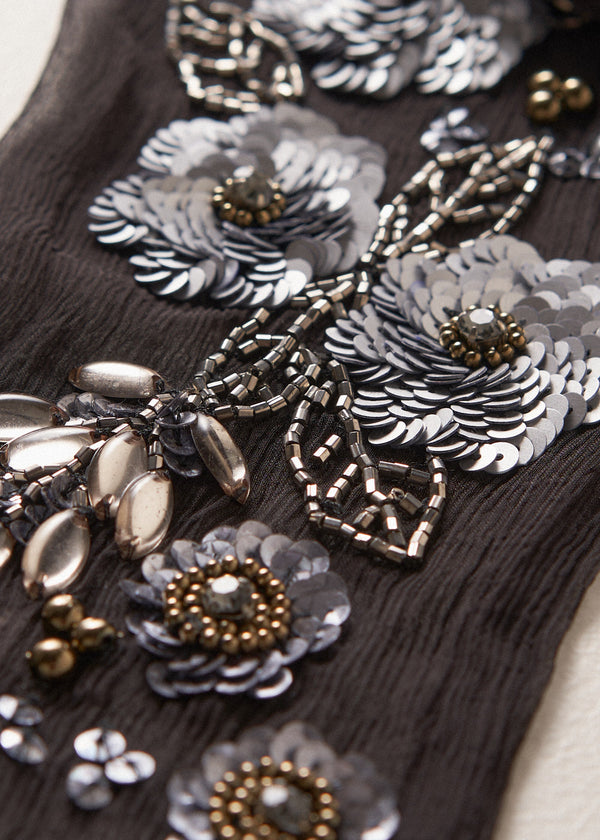 Close up of grey sequin flower detail on a black chiffon scarf