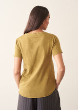 A woman wearing a olive green v-neck t-shirt with grey charcoal stripe trousers and sandals