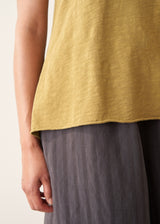 A woman wearing a olive green v-neck t-shirt with grey charcoal stripe trousers and sandals