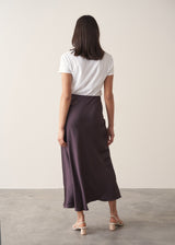 Woman wearing burgundy satin slip skirt with white t-shirt and stone knittted waistcoat