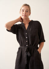 Woman wearing a short sleeve black linen jumpsuit with a button up front and waist tie