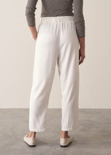 Woman wearing off-white relaxed tapered trousers and a grey stirpe top