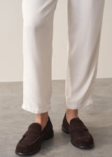 Woman wearing off-white relaxed tapered trousers and a grey stirpe top