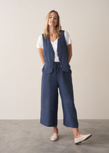 Woman wearing a blue vest and wide-leg pants against a plain background