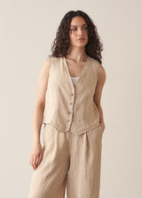 Woman wearing a beige striped linen waistcoat with a white vest top and striped linen trousers