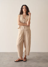 Woman wearing a beige striped linen waistcoat with a white vest top and striped linen trousers