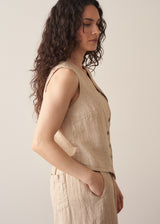 Woman wearing a beige striped linen waistcoat with a white vest top and striped linen trousers