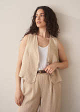 Woman wearing a beige striped linen waistcoat with a white vest top and striped linen trousers