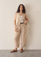Woman wearing a beige striped linen waistcoat with a white vest top and striped linen trousers