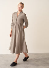 Woman wearing a midi length long sleeve checked dress with button up front.