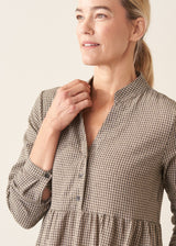 Woman wearing a midi length long sleeve checked dress with button up front.