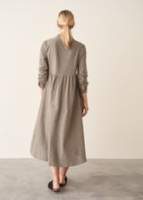 Woman wearing a midi length long sleeve checked dress with button up front.