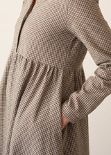 Woman wearing a midi length long sleeve checked dress with button up front.