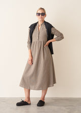 Woman wearing a midi length long sleeve checked dress with button up front.