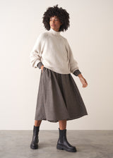 Woman wearing a checked midi dress and chunky boots against a plain background