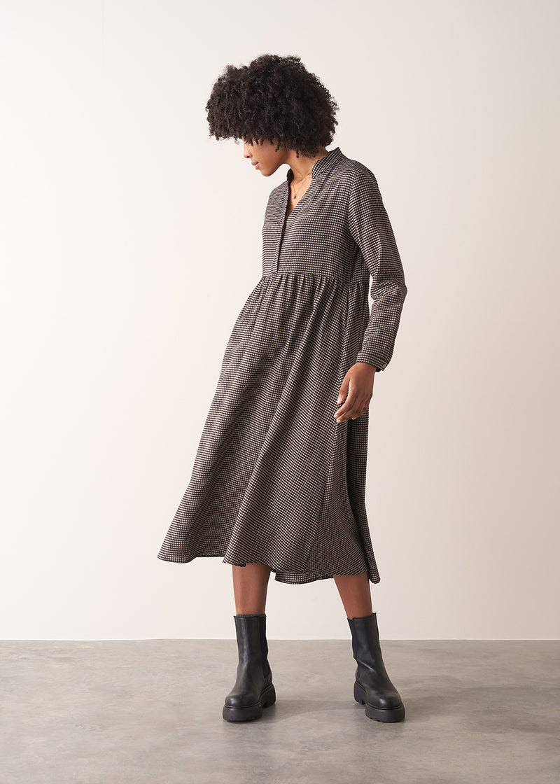 Woman wearing a checked midi dress and chunky boots against a plain background