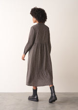 Woman wearing a checked midi dress and chunky boots against a plain background