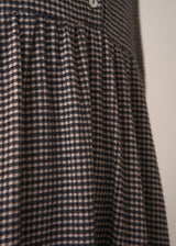 Woman wearing a checked midi dress and chunky boots against a plain background