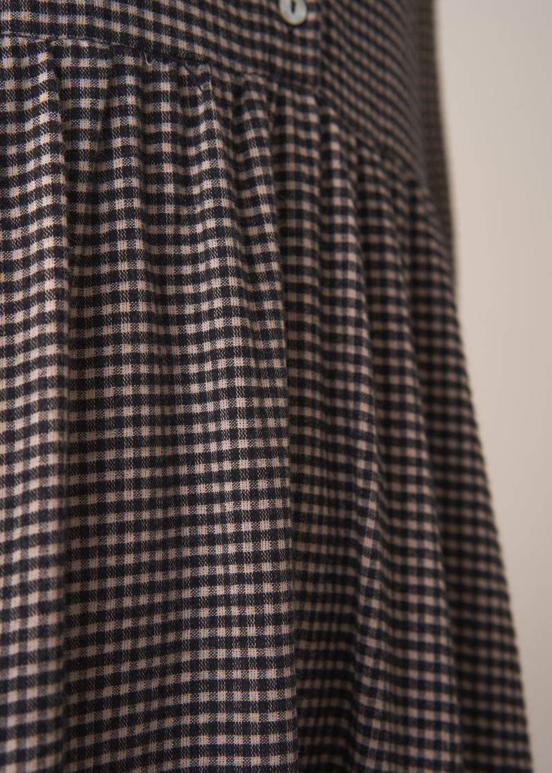 Woman wearing a checked midi dress and chunky boots against a plain background